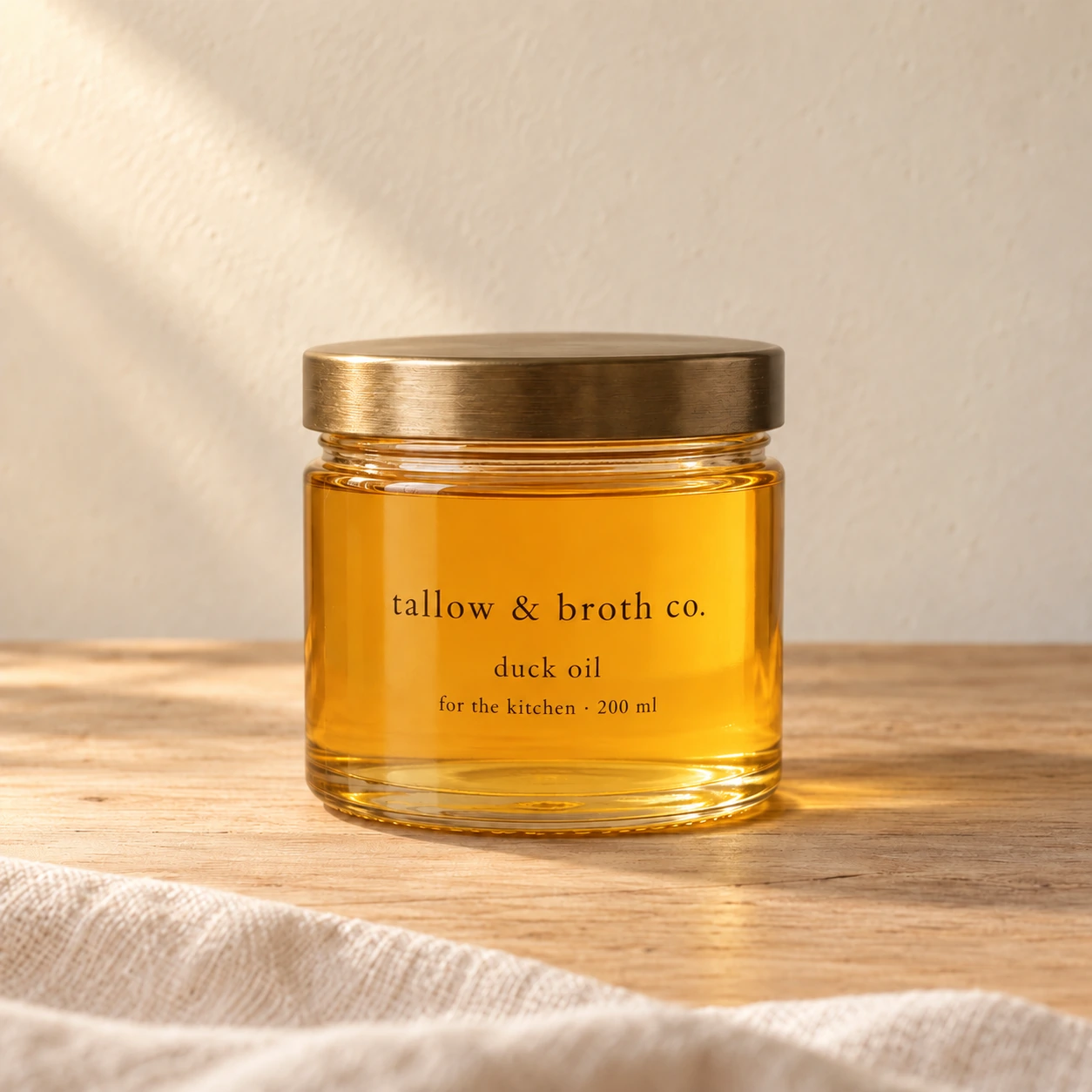 A 200 ml glass jar of amber duck oil with a brass lid and a minimalist serif label on warm oak